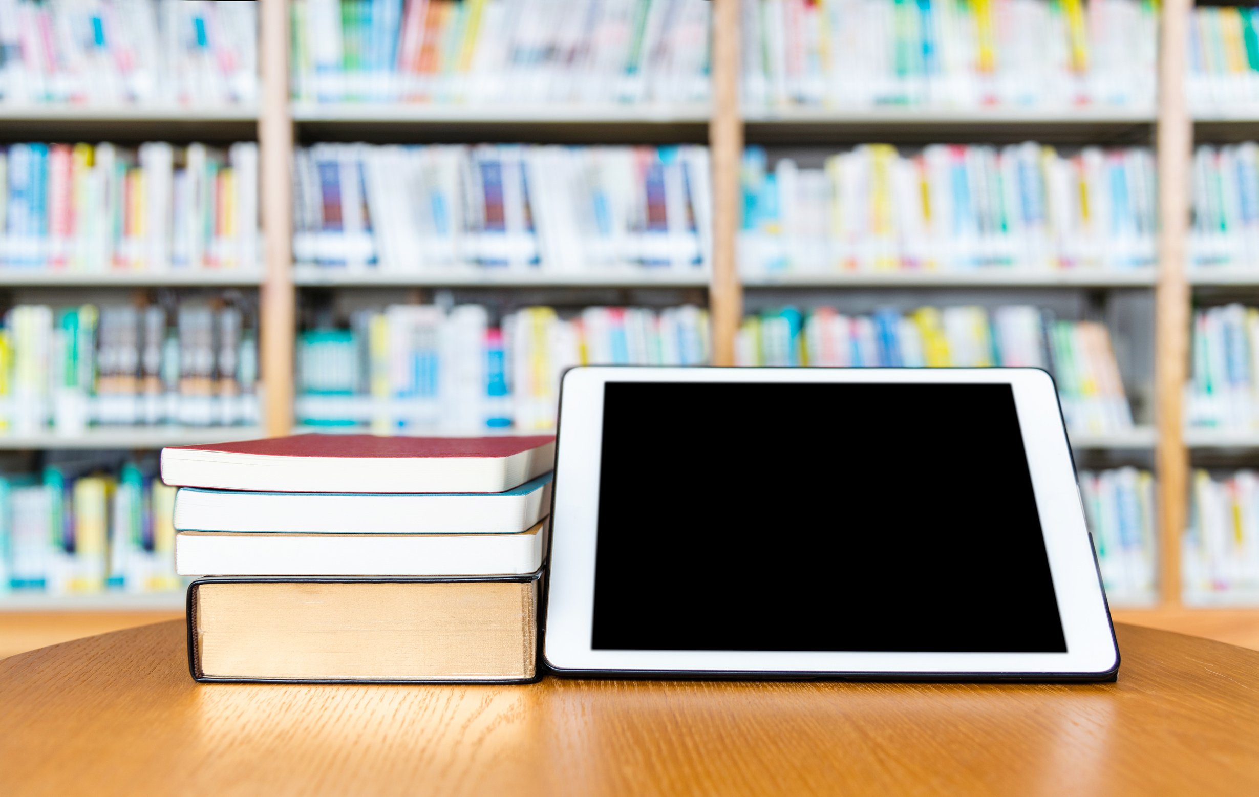 Digital tablet and books on wooden table